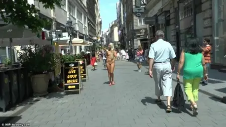 Naken blondin går längs upptagna gator