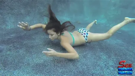 En smal tjej försöker suga en gummikuk under vatten