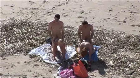 En mängd killar på stranden släpper in en cirkel med två prostituerade